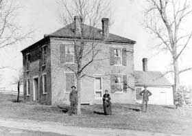 Brick two-story house with three people in front.